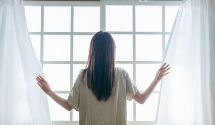 カーテンを開ける女性